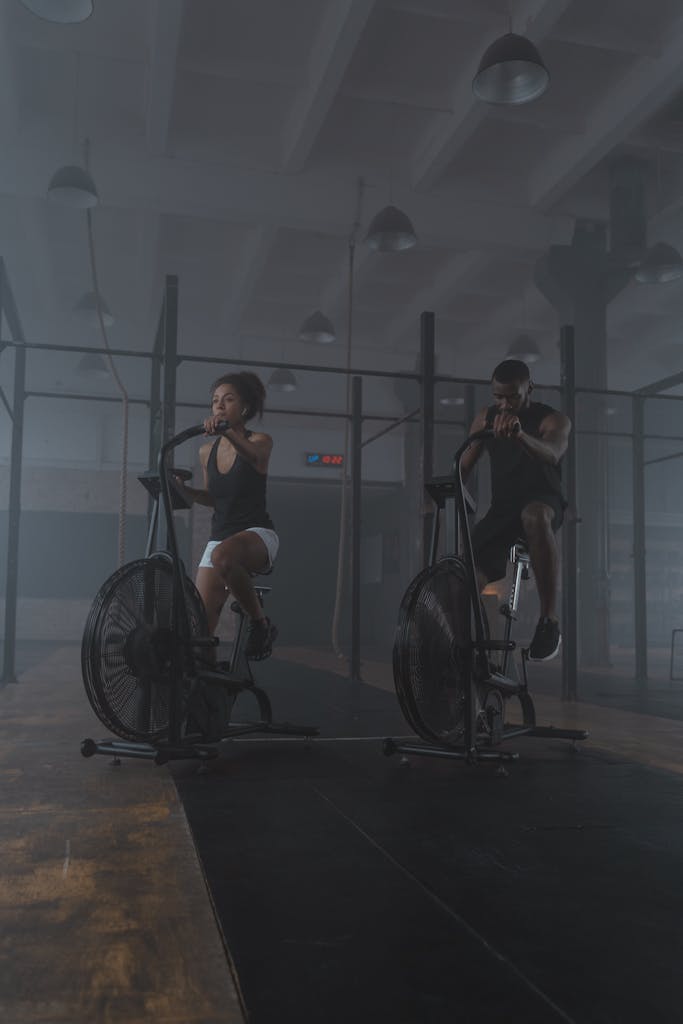 Deux personnes s'entrainent sur des velo stationnaires dans un gymnase